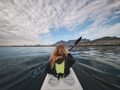 Cape Town, South Africa – April 19, 2023: A closeup of a Young, blonde girl kayaking with Table Mountain in the background Cape Town, South Africa