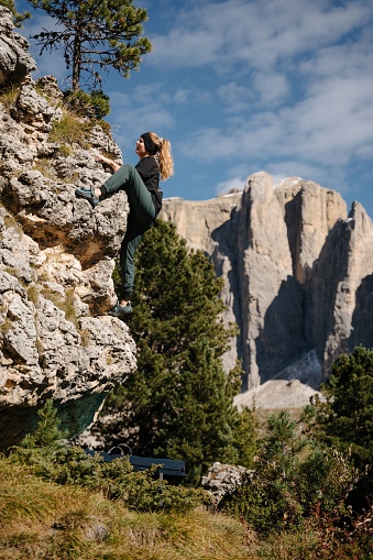 A closeup of a young, attractive blonde woman climbing bouldering in the Dolomites, Italy