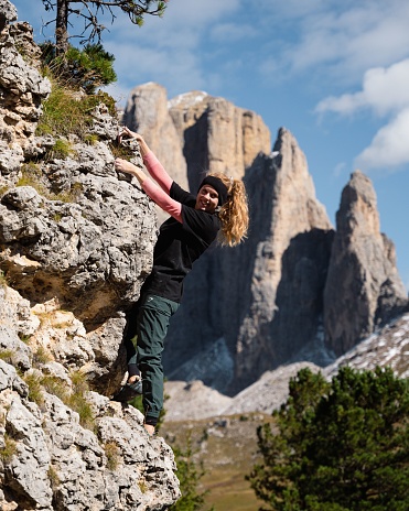 A closeup of a young, attractive blonde woman climbing bouldering in the Dolomites, Italy