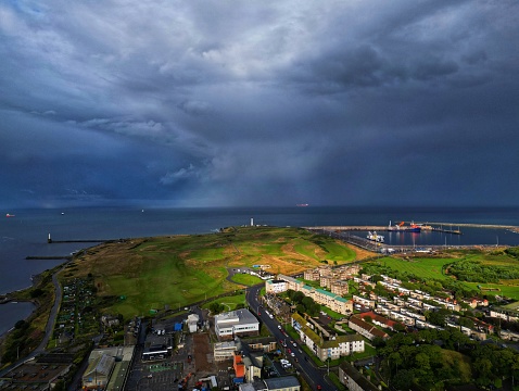 A storm over the North Sea in Aberdeen, Scotland with the port of Aberdeen on the horizon and the historical residential area of Torry in the foreground.