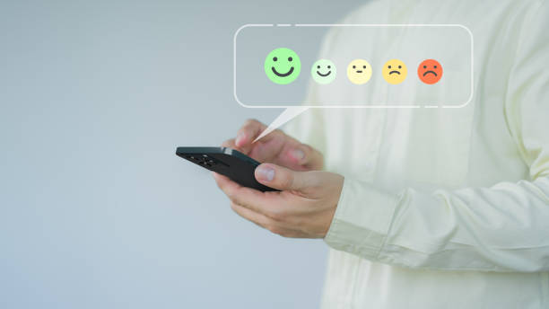 istock Client hands using a mobile phone with pop up smile face icon for feedback review satisfaction service opinion and testimonial. Customer service experience assessment and business satisfaction survey. 1649454913