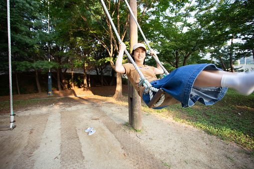 Young woman swinging on swing joyfully in park