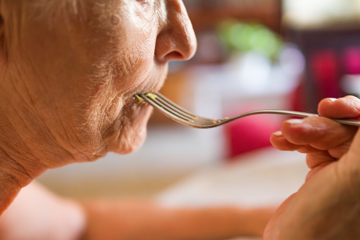 close-up shot of an unrecognizable old woman eating with a fork with her mouth full.gluttony and binge eating concept.
