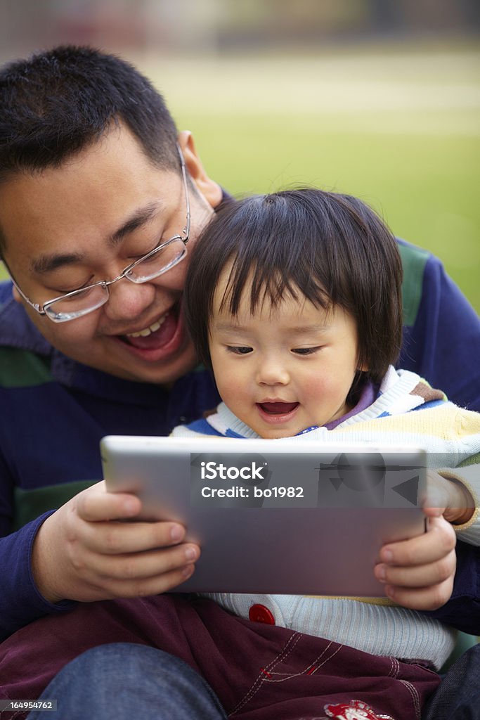 Joven padre con su hija usando tableta al aire libre - Foto de stock de 12-23 meses libre de derechos