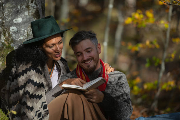 istock A couple in love is sitting in the forest with a book. 1649551440