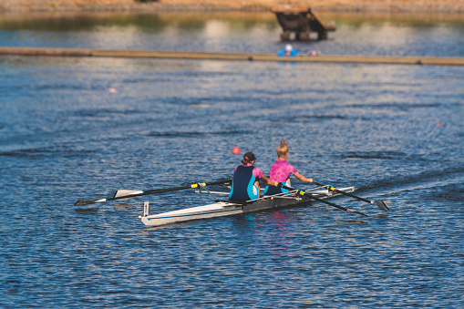 Group of rowing team female girl athletes sculling during competition, kayak boats race in a rowing canal, regatta in a summer sunny day, women canoeing water sports team training in river