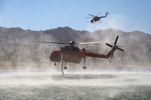 Cal Fire helicopters fills up from a lake to fight nearby fire.  Shot in Moreno Valley, California in July of 2023.