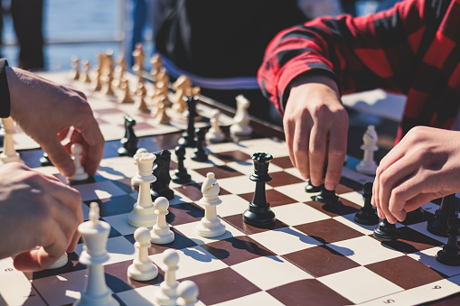 Chess tournament, kids and adults participate in chess match game outdoors in a summer sunny day, players of all ages play, competition in chess school club with chessboards on table