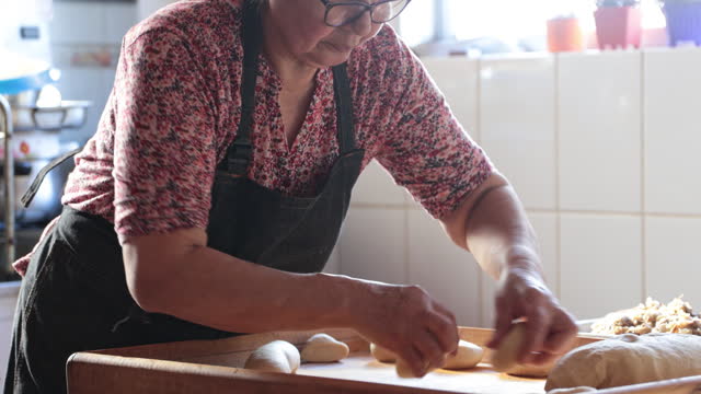 Latin Woman Kneading Dough with a Rolling Pin, for making Empanadas in her Countryside Home Kitchen