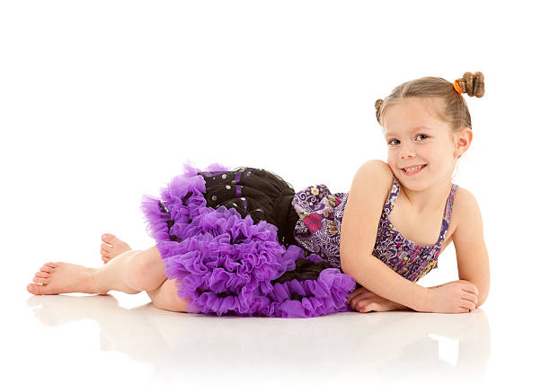 A young girl wearing a flared out black and purple dress dances and poses. Studio shots, isolated on white background.