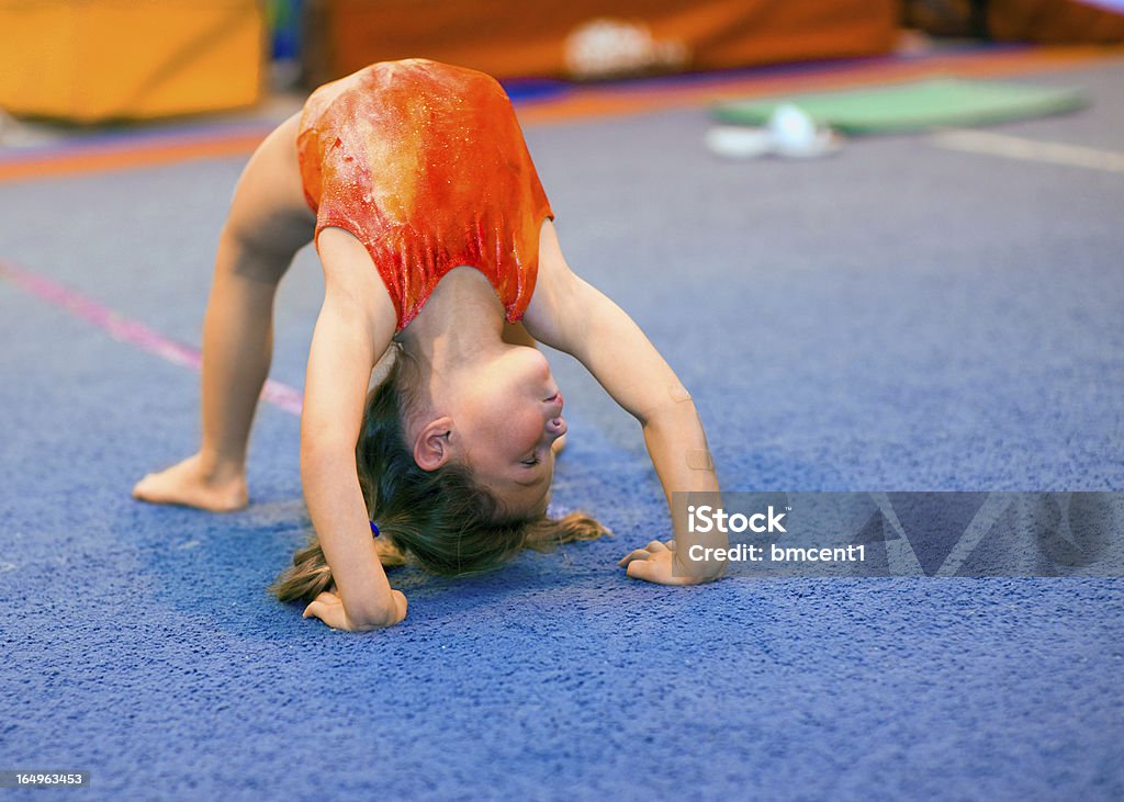 Toddler girl in leotard doing a bridge Children can excel at gymnastics, even beginning at a very young age! This toddler girl, aged 4, is demonstrating a Bridge position by pushing off her hands and feet and thrusting her back upwards. She is looking right. Gymnastics Stock Photo