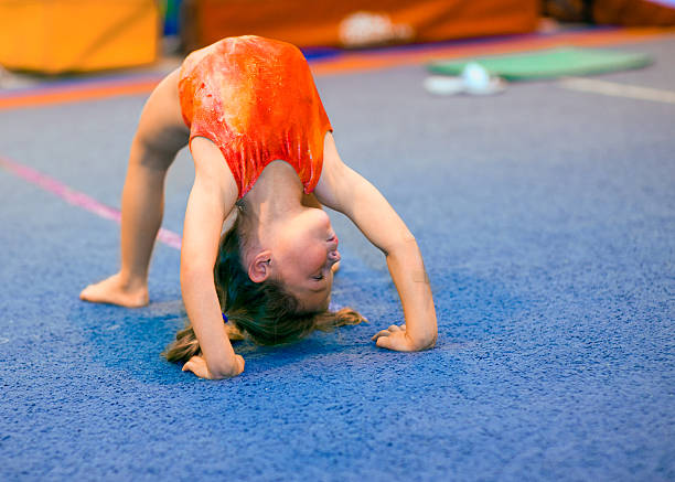 Toddler girl in leotard doing a bridge Children can excel at gymnastics, even beginning at a very young age! This toddler girl, aged 4, is demonstrating a Bridge position by pushing off her hands and feet and thrusting her back upwards. She is looking right. gymnastics stock pictures, royalty-free photos & images