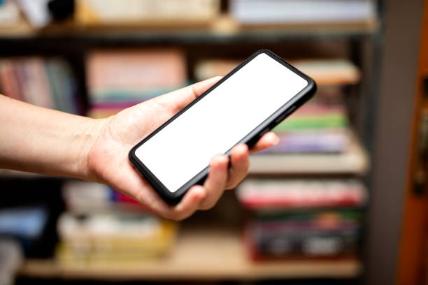 Hand holding mockup smartphone in a blurred bookstore interior Hand holding mockup smartphone in a blurred bookstore interior bookstore stock pictures, royalty-free photos & images