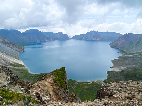 Changbaishan, Jilin, China- August 27, 2023: Changbai Shan Mountain's 'Heavenly Lake' in Jilin Province is a lake that straddles the border between China and North Korea and is the source of the Songhua River. The crater in which the lake sits was originally an active volcano which erupted 3 times from the 16th century. Changbai Mountain is divided into four slopes: North, West, South, and East. The South Slope is closed to travelers due to construction and nature protection.  Here is the panorama of the lake from the South Slope.