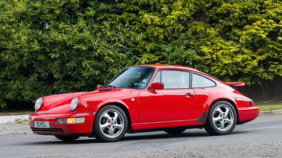 Whittlebury,Northants,UK -Aug 27th 2023:  1990 red Porsche 911  car travelling on an English country road