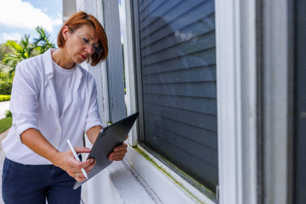 leckageprüfung von fenstern mit digitalem tab: rothaariger sachbearbeiter, der fenster im freien auf anzeichen von undichtigkeiten, wasserflecken oder schimmel untersucht - preventative maintenance stock-fotos und bilder