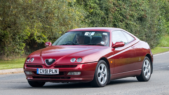 Whittlebury,Northants,UK -Aug 27th 2023: 2001 red Alfa Romeo GTV car travelling on an English country road