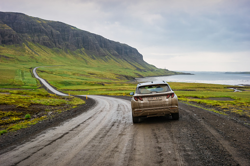 SUV stands on a dirt road near a fjord on Snaefellsnes Peninsula, Iceland on a rainy day.