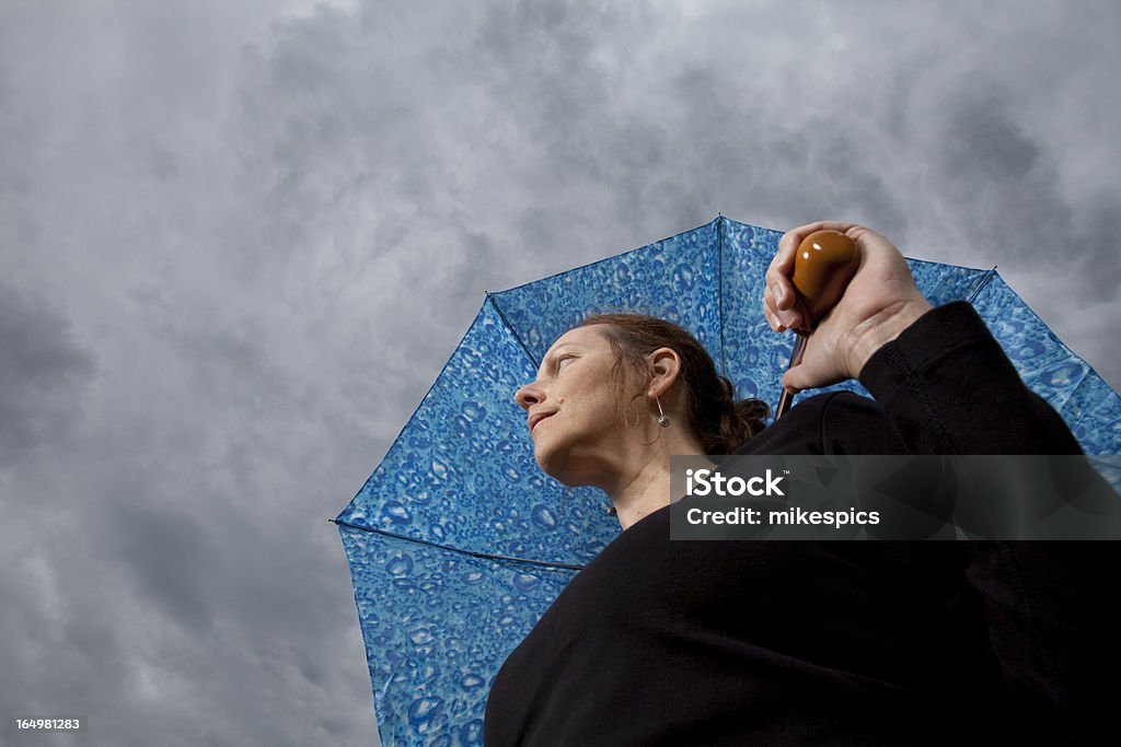 Ângulo baixo de uma mulher com guarda-chuva olhando tempo de tempestade - Foto de stock de Examinar royalty-free
