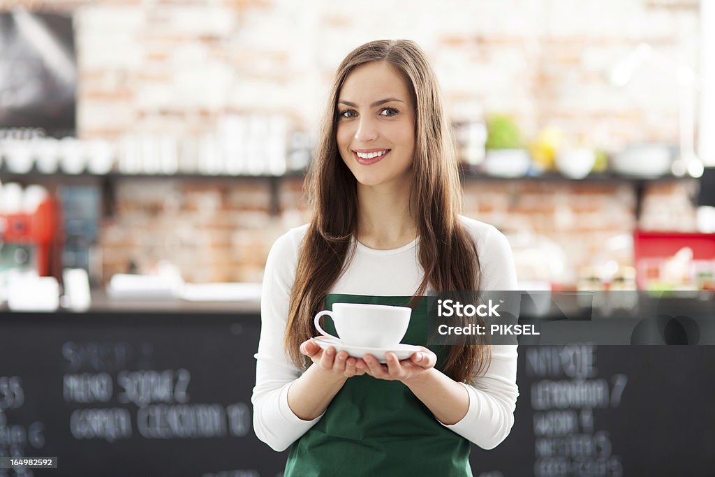 Waitress holding cup of coffee in cafe Adult Stock Photo