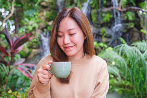 Elegant young Caucasian woman drinking coffee at the sidewalk cafe