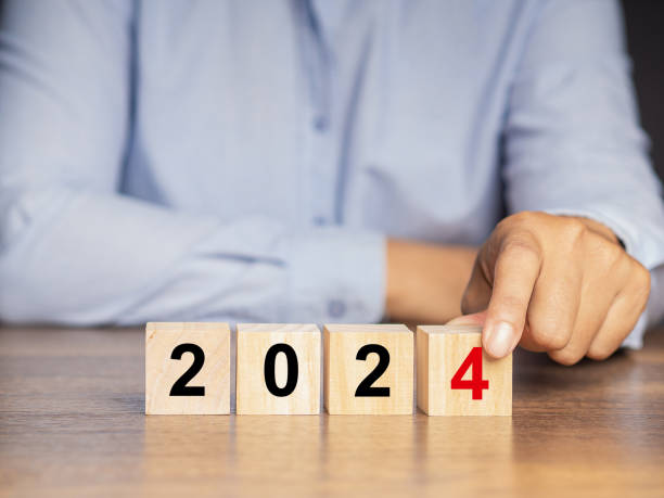 istock Hand holding a wooden cube with the letters 2024 while sitting at the table 1649878840