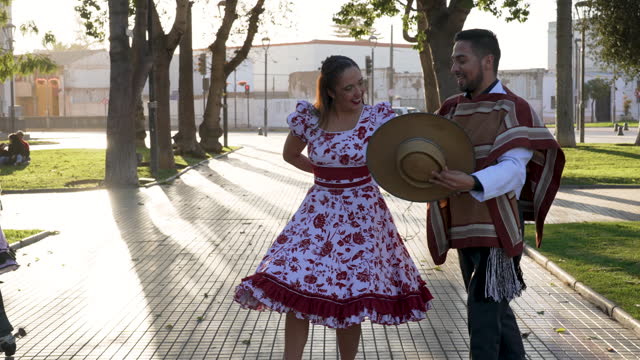 men in huaso costumes lead the women by the arm to dance the cueca in the street
