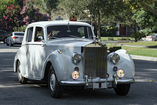 London, UK - 1 April, 2021: an old vintage white Cadillac car parked on a residential city street in London, UK.