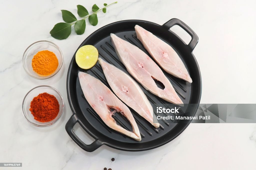 Fresh whole Silver Pomfret fish or butter fish or Poplet cut into slices. cleaned and ready for frying along with spices. ingredients and recipe background with copy space Silver Colored Stock Photo