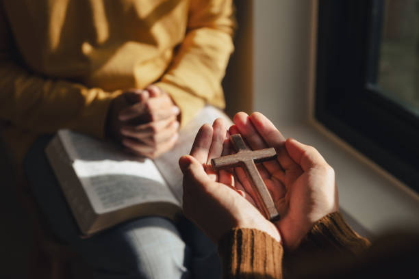 um homem segura as mãos da cruz e da bíblia sagrada pela janela da igreja - religious text cross protestantism reading - fotografias e filmes do acervo