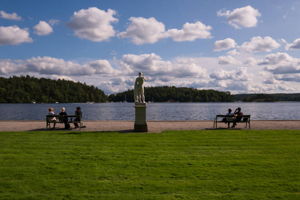 ogrody pałacu drottningholm w jasny letni dzień, z posągiem przed jeziorem i turystami siedzącymi na ławkach w parku. - people full length palace sweden zdjęcia i obrazy z banku zdjęć