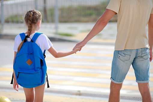 Father and daughter  cross the pedestrian crossing. Back to school. Child and dad go to school