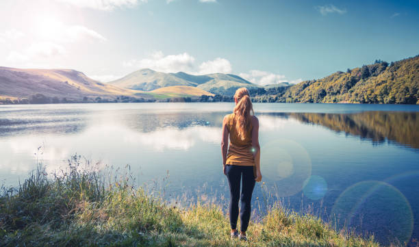 Mujer de pie disfrutando de la vista del lago- Auvernia en Francia (lago de Guery) - viaje, relajante, concepto de paisaje tranquilo - foto de stock