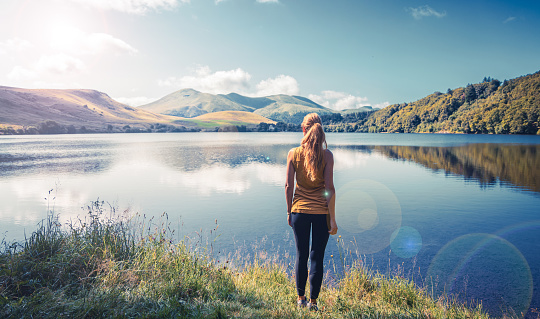 Woman standing enjoying view of lake- Auvergne in France ( Guery lake)- travel, relaxing, calm landscape concept
