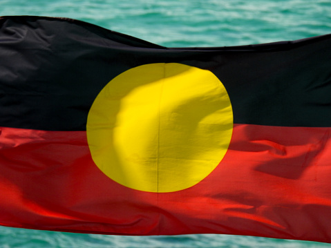 The Australian Aboriginal flag on a flagpole with the background of Pacific Ocean at Bondi Beach, Sydney.  This image was taken on a partly sunny afternoon on 31 August 2023.