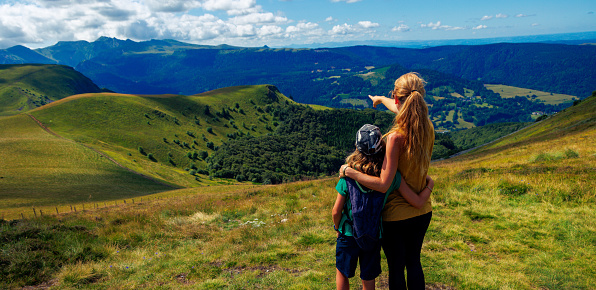 Mother and son enjoying mountain panoramic view- Massif central, Auvergne in France, volcanic landscape- family sport, travel, tourism, adventure concept