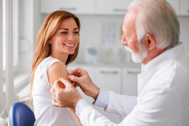 Doctor applying medical patch to female patient after vaccination stock photo
