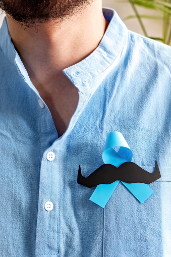 Man in blue shirt with Blue Ribbon and paper mustache for supporting people living and illness.