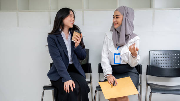 istock Two friendly Asian female job candidates enjoy talking while waiting for a job interview. 1650159098