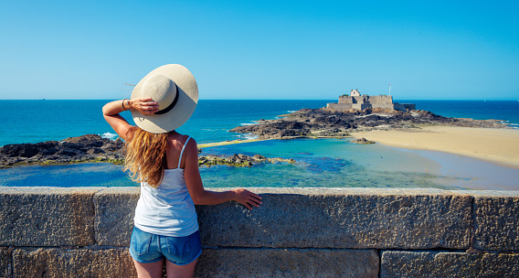 Rear view of woman looking at beach and fort, Saint Malo in France