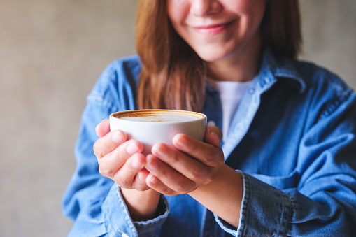 Closeup image of a woman holding a cup of hot coffee