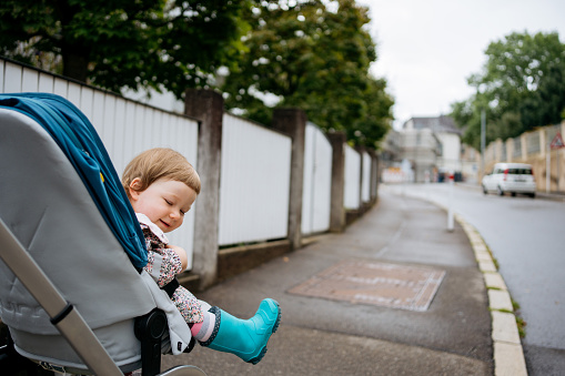 A happy little girl sits in a pram driving down the street