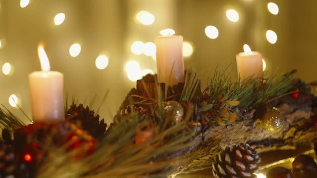 Christmas candles adorned with tree ornaments in a cozy setting with warm home lighting.