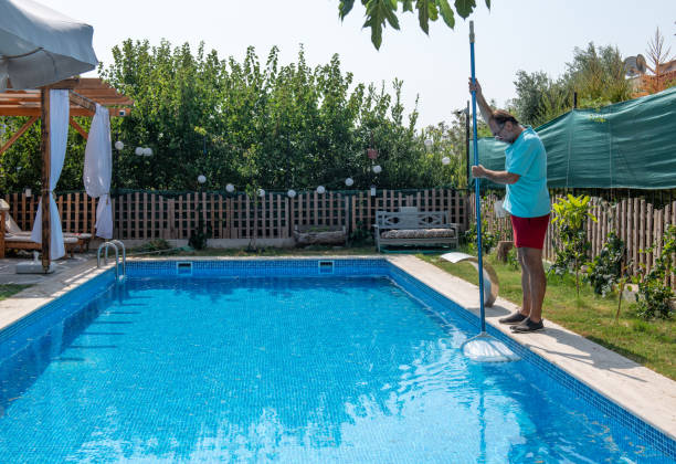 istock Man in flip flops cleaning the swimming pool with a net. 1650169350