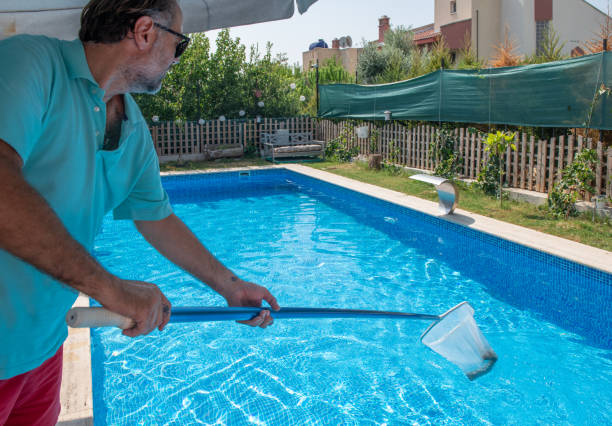 istock Man in flip flops cleaning the swimming pool with a net. 1650169355