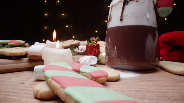 A Christmas table adorned with gingerbread cookies, marshmallows, and cocoa. Decorations and gifts are scattered everywhere. Dolly slider extreme close-up.