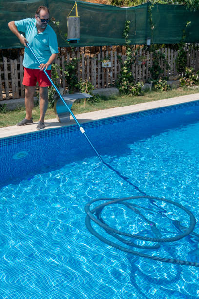 istock Man in flip flops cleaning the swimming pool with a net. 1650178388