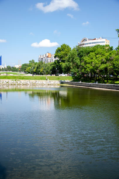 A pond surrounded by a monument and green trees with a lawn. High quality photo