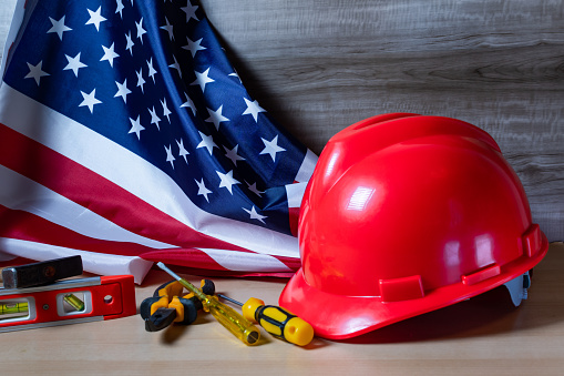 Red helmet and tools on large American flag, Labor day background concept.