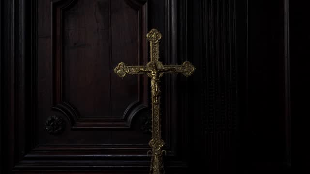 Large golden crucifix inside a dark sacristy.